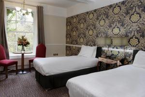 Risley Hall Hotel في Risley: غرفة فندقية بسريرين وكرسي احمر