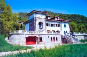 un grande edificio in pietra con una porta rossa su una collina di Villa Hélène a Solto Collina
