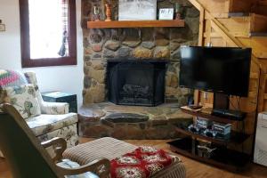 uma sala de estar com uma lareira de pedra e uma televisão em Waterwheel Cabin by the Creek em Murphy