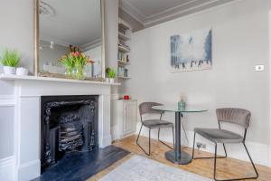 - un salon avec une cheminée, une table et des chaises dans l'établissement Vogue 1 bedroom Pimlico flat near Victoria Station, à Londres