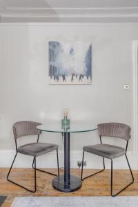 2 chaises et une table en verre dans une pièce dans l'établissement Vogue 1 bedroom Pimlico flat near Victoria Station, à Londres