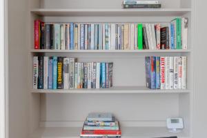 a book shelf filled with lots of books at Vogue 1 bedroom Pimlico flat near Victoria Station in London