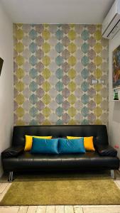 um sofá preto com almofadas amarelas e azuis num quarto em Roma Caracalla apartament with garden em Roma