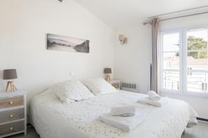 a white bedroom with a bed and a window at Appartement Valène in La Flotte