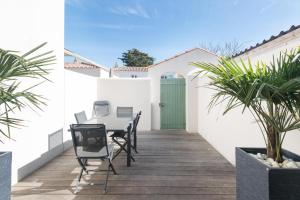a patio with a table and chairs and a green door at Appartement Valène in La Flotte