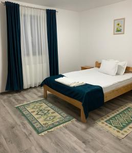 - une chambre avec un lit doté d'une couverture bleue et de rideaux dans l'établissement Pensiunea Denisa & Madalina, à Beliş