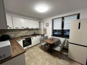 Una cocina con mesa y sillas y un refrigerador. en D&M APARTMENTS 1, en Satu Mare