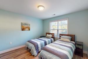 two beds in a room with blue walls and a window at The Lake Keziah House in Southport