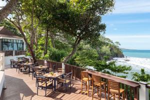 a deck with tables and chairs overlooking the ocean at Avani Plus Koh Lanta Krabi Resort in Ko Lanta