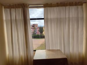 een kamer met een raam met witte gordijnen bij Habitación Confortable frente al Hospital Regional Ramiro Priale in Huancayo