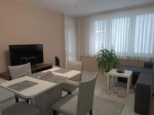 uma sala de estar com uma mesa e cadeiras e uma televisão em City Apartment em Gotse Delchev