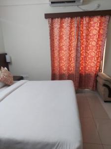 ein Schlafzimmer mit einem Bett und einem Vorhang mit einem TV in der Unterkunft Eden 2 bhk Service Apartments in Bangalore