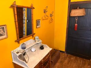 ein Badezimmer mit einem Waschbecken, einem Spiegel und einer Tür in der Unterkunft les loges du chaudron in La Chapelle-aux-Choux