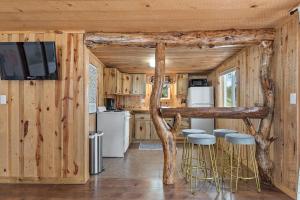 a log cabin kitchen with bar stools and a tv at The Monet- BHBungalows #1 in Custer