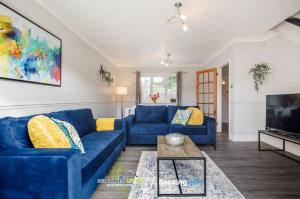 a living room with a blue couch and a tv at Ascot, Pet Friendly, Detached 4 Bedroom House By Sentinel Living Short Lets & Serviced Accommodation Windsor Ascot Maidenhead With Free Parking in Ascot