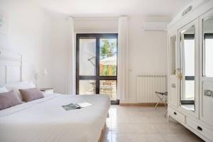 a white bedroom with a large bed and a window at Biancaleuca Rooms & Suite in Leuca