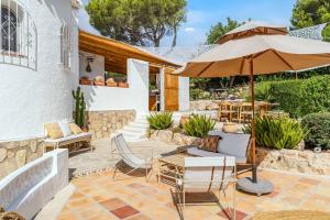 un patio con mesa y sombrilla en Villa Hermosa Javea, en Jávea