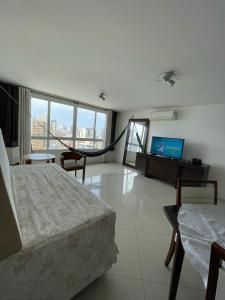 a bedroom with a bed and a desk with a television at Apartamento com Vista Oceânica in Torres