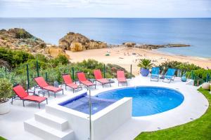 a pool with chairs and a beach in the background at Villa de la Plage in Albufeira