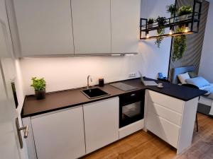 una piccola cucina con armadi bianchi e lavandino di Modernes Apartment im Zentrum von Karlsruhe a Karlsruhe