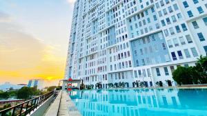 a large building with a swimming pool in front of it at Patraland Urbano Apartment by SiniBobo in Bulanbulan
