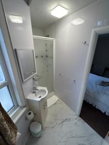 a white bathroom with a sink and a shower at Earls Court Hotel in London