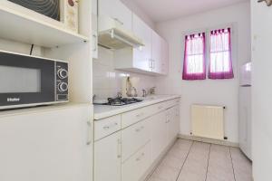 une cuisine avec des armoires blanches et un micro-ondes dans l'établissement Escapade tout près du Port et de la plage, à Saint-Gilles-Croix-de-Vie