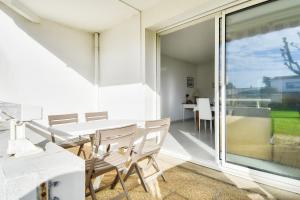ein Esszimmer mit einem Tisch und Stühlen sowie einem großen Fenster in der Unterkunft Escapade tout pres du Port et de la plage in Saint-Gilles-Croix-de-Vie