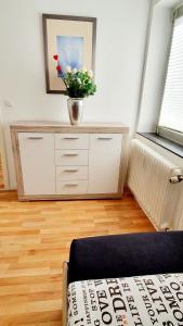 a room with a dresser with a vase of flowers on it at Gemütliche Monteurwohnung in Oberhausen in Oberhausen +3 photos