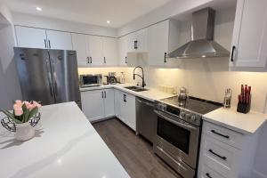a kitchen with white cabinets and stainless steel appliances at Stylish Home in Prime Location North of Toronto in Richmond Hill +44 photos