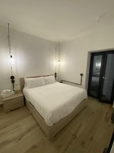 a bedroom with a white bed and a wooden floor at Emerald Apartment in Valmontone