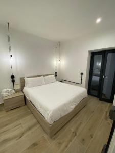 a bedroom with a white bed and a wooden floor at Emerald Apartment in Valmontone
