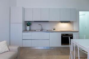 - une cuisine avec des placards blancs, un évier et une table dans l'établissement Estia Suites, à Villasimius