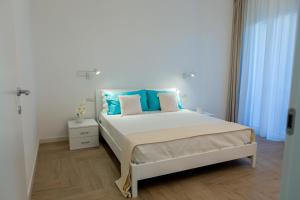 a bedroom with a large bed with blue pillows at Estia Suites in Villasimius
