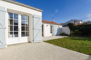 a house with white doors and a driveway at Maison pour 6 au coeur de Bretignolles-sur-Mer in Brétignolles-sur-Mer