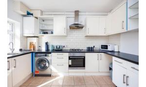 a kitchen with white cabinets and a washing machine at Shortlet Express, Large 4 bedroom house, 2 baths in East Ham in London