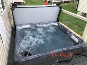 a hot tub sitting on a deck in a yard at Tattershall Lakes The Oakley Caravan 8 berth, Hot tub & WiFi in Tattershall