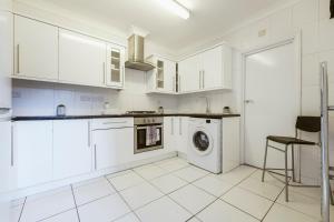 cocina con armarios blancos y lavadora en Stratford Double Rooms - 29 en Londres