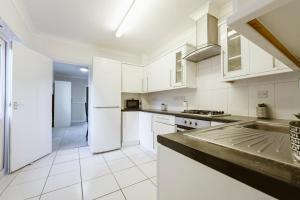 a kitchen with white cabinets and a refrigerator at Stratford Double Rooms - 29 in London