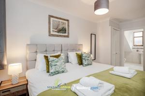 a bedroom with a large white bed with pillows at 4 Bedroom House By Sentinel Living Short Lets & Serviced Accommodation Windsor Ascot Maidenhead With Free Parking & Pet Friendly in Maidenhead