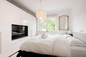 a white bedroom with a bed and a tv at Luminous Penthouse with Open Sky Terrace in Sandweiler