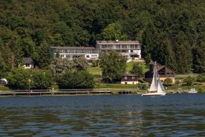 ein Segelboot im Wasser vor einem großen Haus in der Unterkunft PlusNaturHotel direkt am Ederseeufer Waldhotel Wiesemann und Ferienapartments in Waldeck