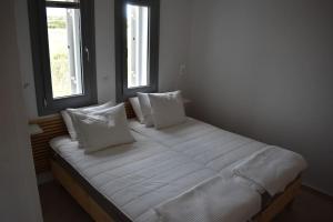 un letto con lenzuola e cuscini bianchi in una stanza di Cycladic house on Agios Spyridonas beach a Andiparos