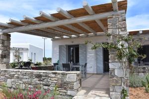 une terrasse avec un mur en pierre et une pergola en bois. dans l'établissement Cycladic house on Agios Spyridonas beach, à Andiparos