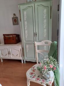 a room with a cabinet and a chair and flowers at Apartment Bella Rosa in Koper