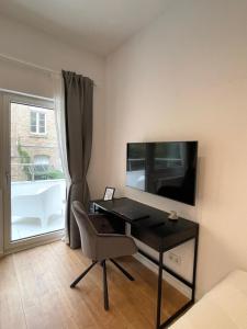 a room with a desk with a television and a chair at Modernes Apartment im Zentrum von Karlsruhe in Karlsruhe