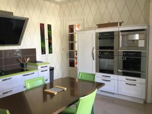 a kitchen with a wooden table and green chairs at Villa Castalie - Maison de maître, grande piscine et jacuzzi, classée 5 étoiles in Montrichard