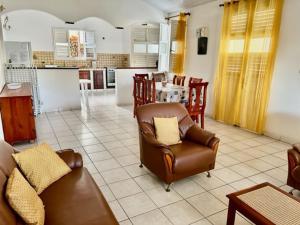 a living room with a couch and chairs and a kitchen at Cloison du BONHEUR in Le Lamentin