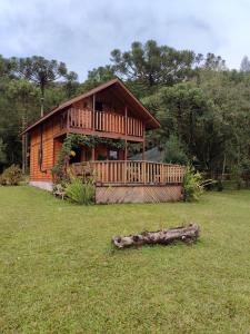 a large wooden house with a log in the grass at Pousada Vale da Imbuia chalé para temporada in Urubici