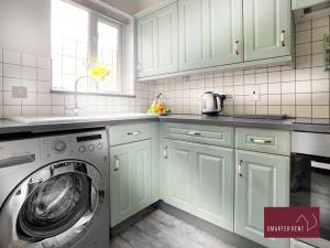 een keuken met groene kasten en een wasmachine bij Knaphill - 2 Bed House - Private Garden & Parking in Brookwood